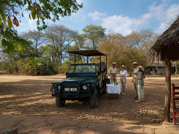 Rafraîchissements servis près du 4×4 à l'ombre d'un boma