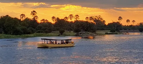 Bateau de safari naviguant sur un fleuve africain au coucher du soleil