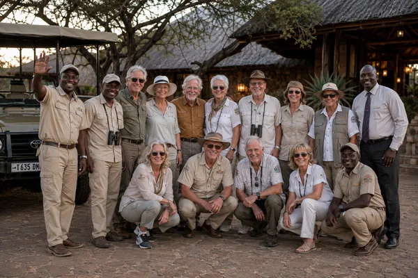 Groupe de voyageurs et guides réunis devant un lodge au crépuscule